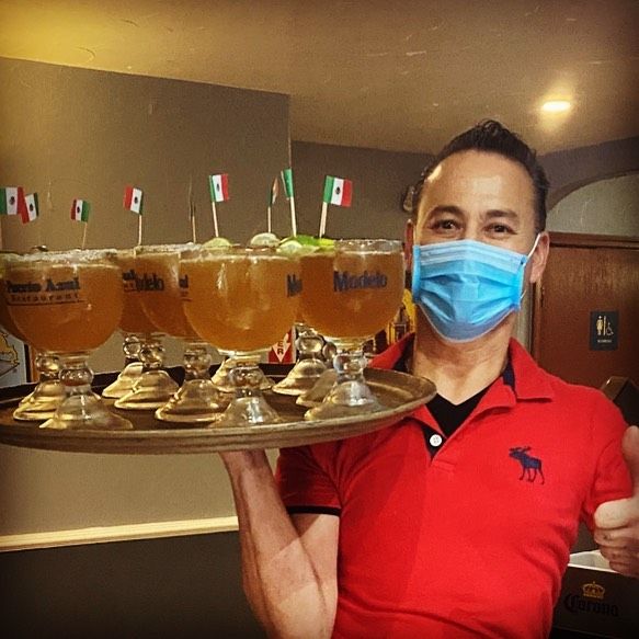 Server carrying a tray of micheladas