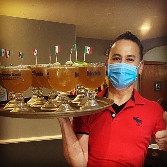 A server carrying a tray of micheladas